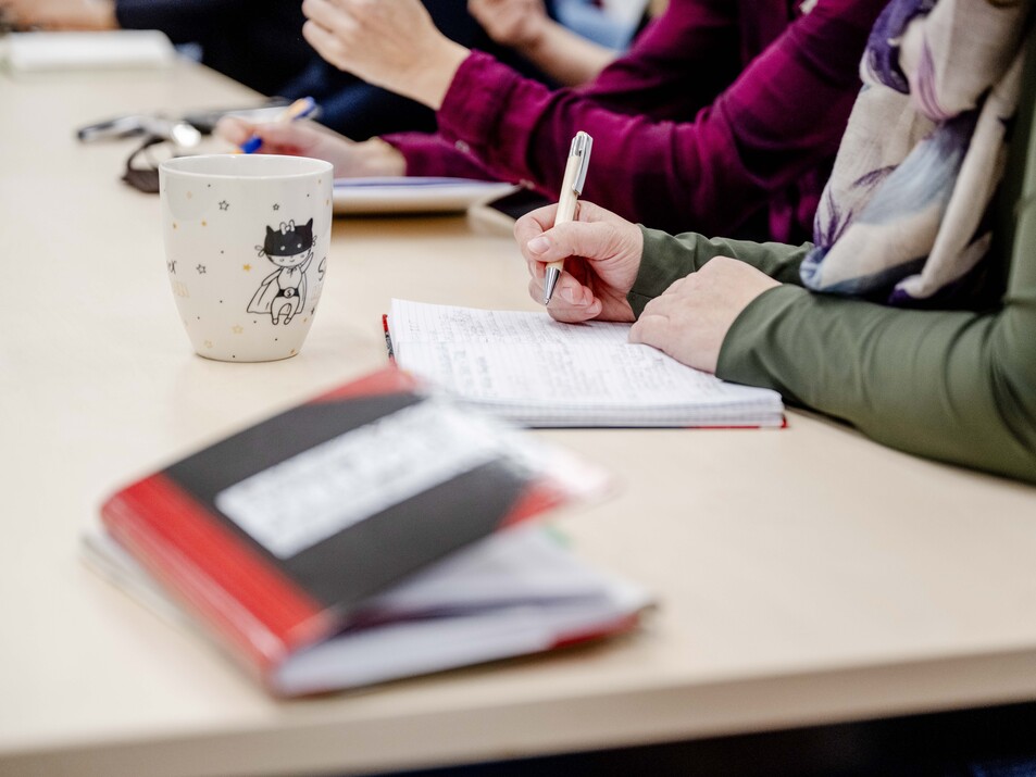 Tisch in Meeting-Situation, Notizbuch, Person nimmt Notizen